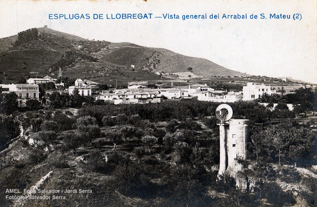 Vista general del desaparegut raval de Sant Mateu. En primer terme, el molí de Ca n’Hospital amb les aspes. 1920-1936.